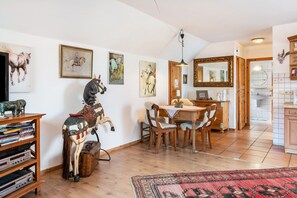 Ein Essbereich mit einem Holztisch, Stühlen, einer Pferdeskulptur und einem Bücherregal mit Büchern und einem Fernseher.