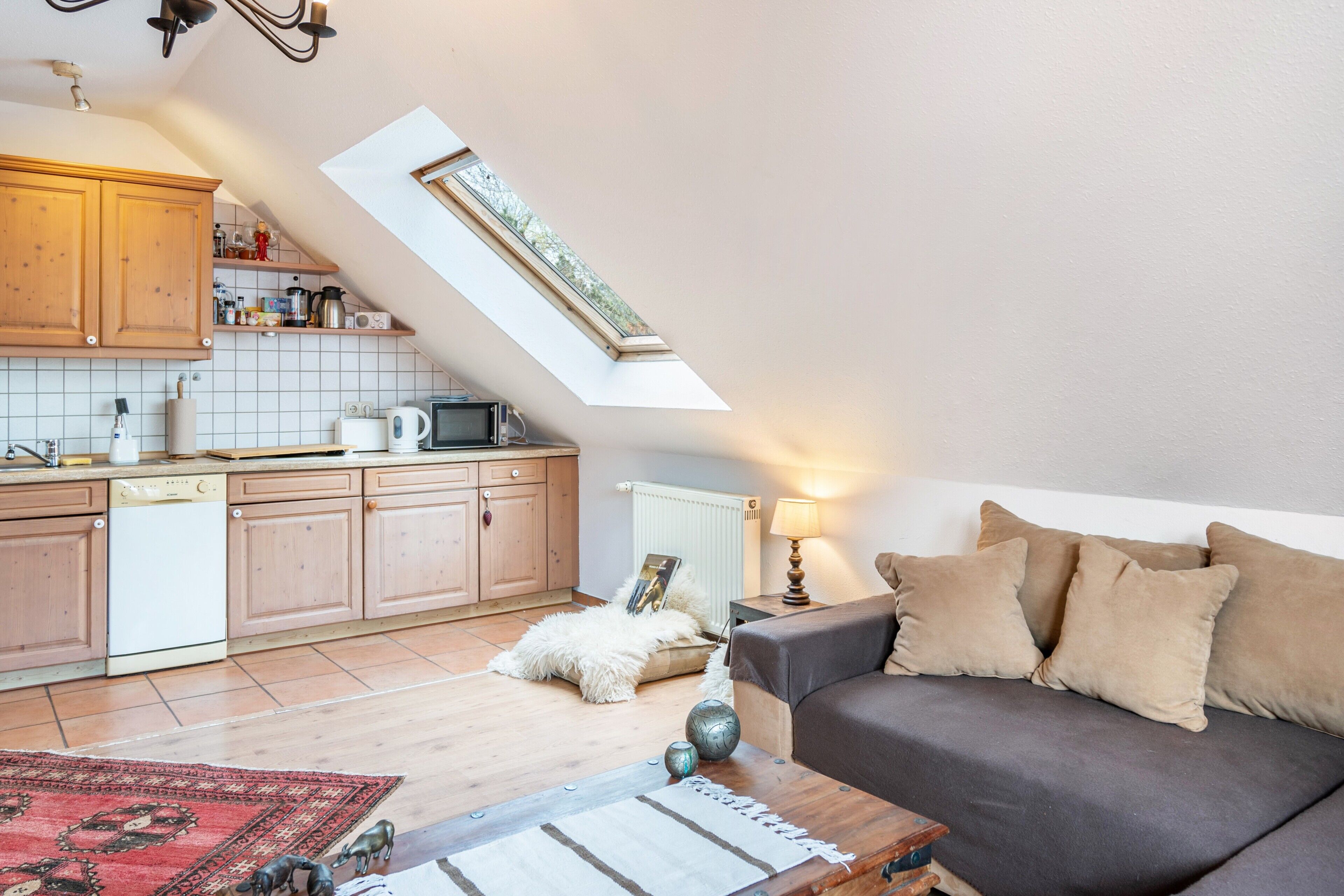 Ein Loft-Wohnraum mit Küche, einer Couch, einem Couchtisch und einem Oberlicht.
