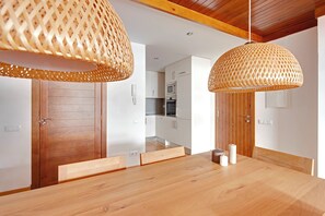 A modern dining area with a wooden table and two woven pendant lights. - Cap 1500 2 by FeelFree Rentals (Baqueira)