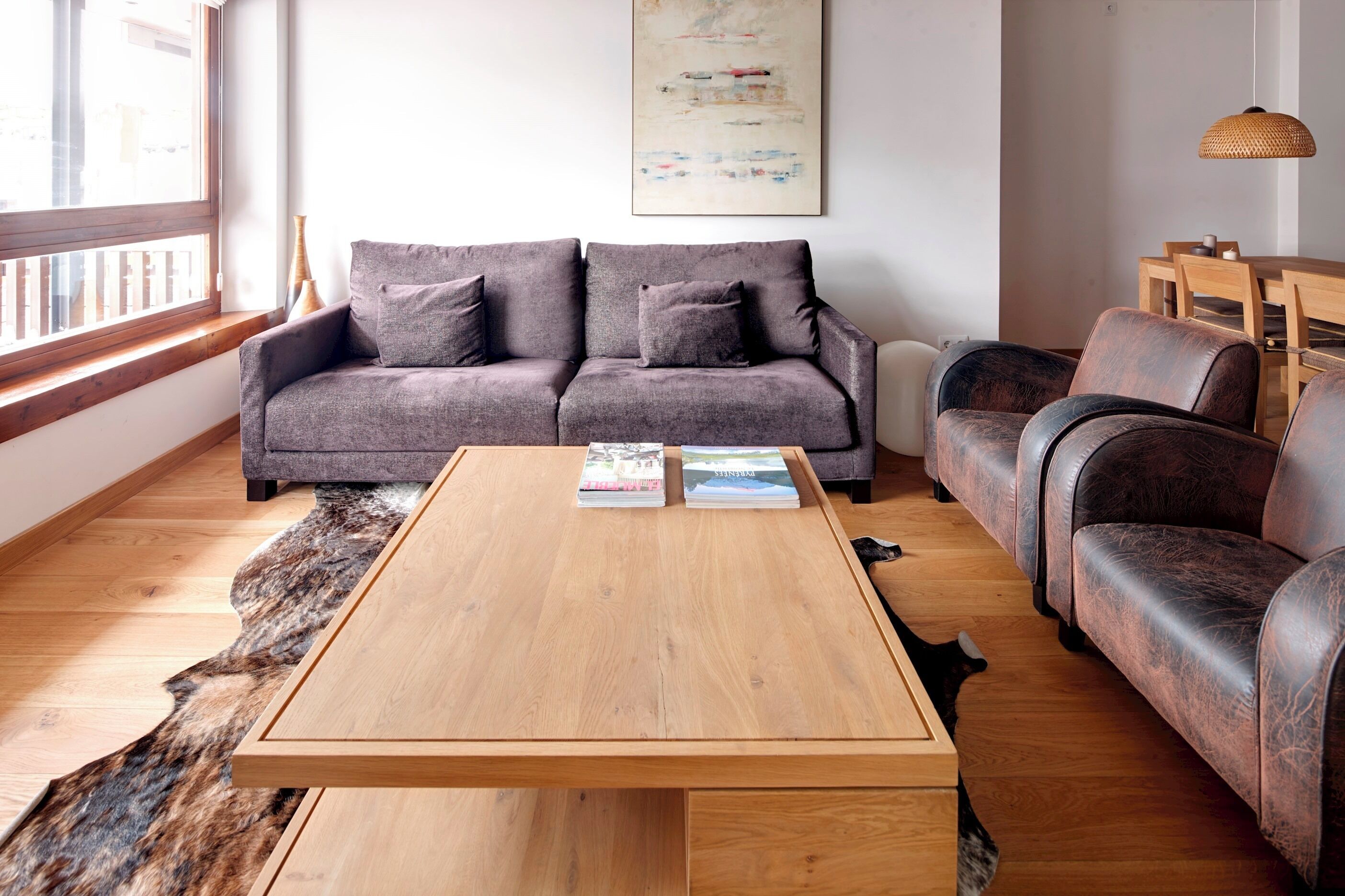 Ein modernes Wohnzimmer mit einem grauen Sofa, einem Holztisch und einer Ledercouch.