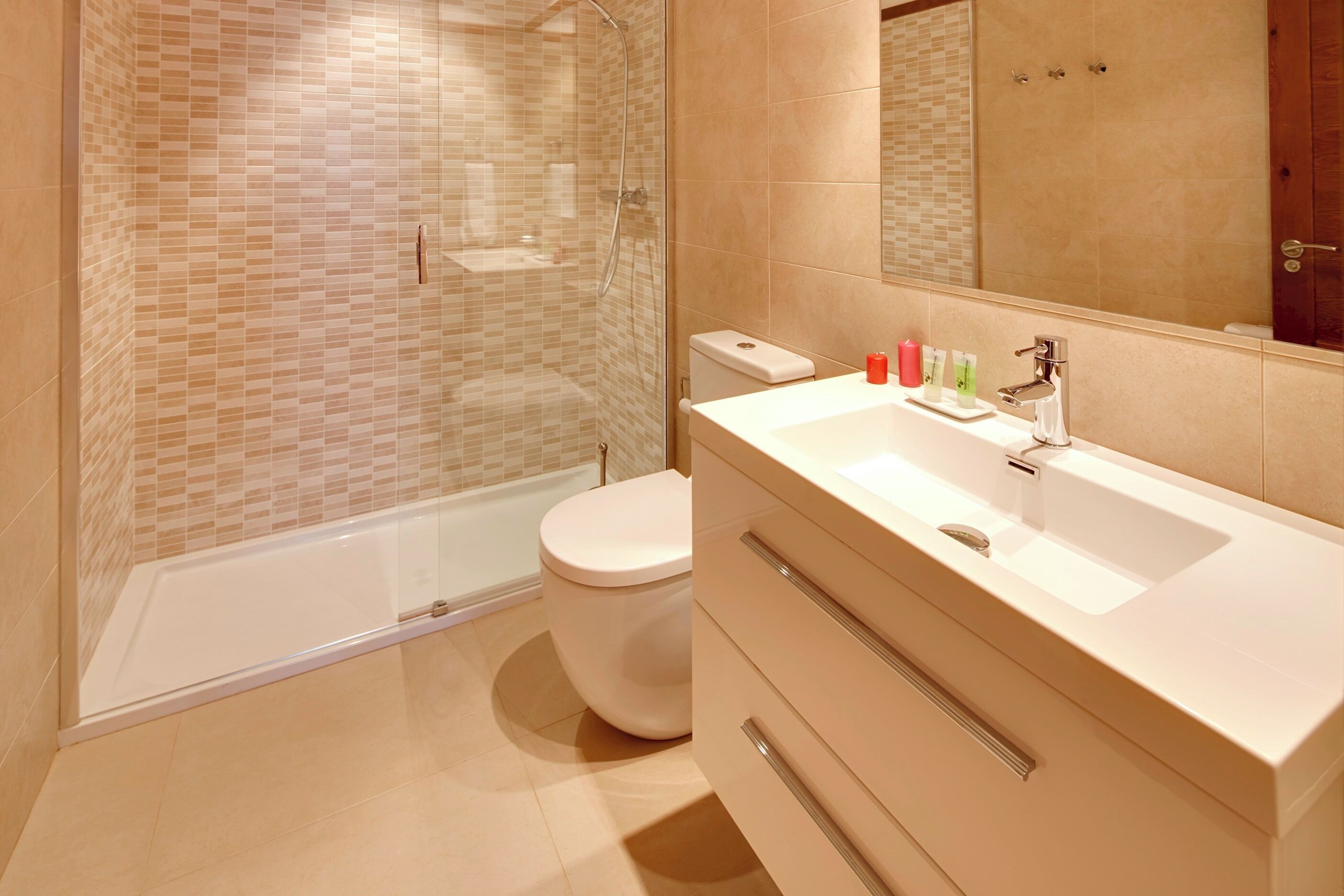 A modern bathroom with a glass-enclosed shower, a white toilet, and a vanity with a sink and mirror.