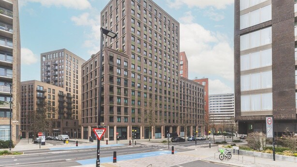 A modern high-rise building with multiple floors, large windows, and a prominent corner entrance. - Modern King’s Cross Central Apartment (London)