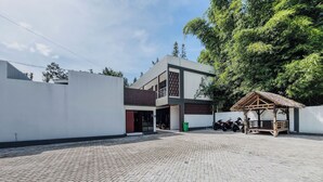 Um edifício moderno com um pátio pavimentado, uma área de estar coberta e uma motocicleta estacionada na frente.