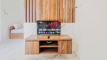 A wooden TV stand with a mounted TV displaying the 'Jurassic World Rebirth' logo, a remote, and a drawer.