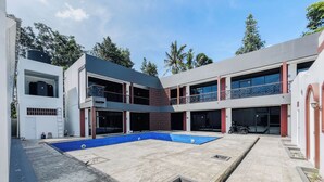 Um edifício moderno com piscina, várias varandas e portão fechado.