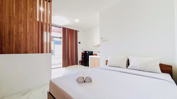 Quarto de hotel com cama, divisória de madeira, escrivaninha e vista para o exterior.