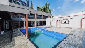 Um edifício moderno com piscina, área coberta e estrutura em dois andares com varandas.