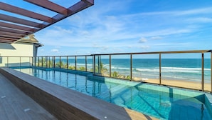 A swimming pool with a glass barrier overlooking the beach and ocean. - Cupe Suites #118 Beachfront by Carpediem (Ipojuca)