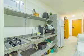 Eine Küche mit Granit Arbeitsplatten, einem Gasherd, einer Spüle und einem Kühlschrank. Über der Arbeitsplatte befinden sich Regale mit verschiedenen Gegenständen, darunter eine Kaffeemaschine und ein Korb.