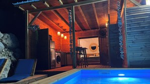 A wooden cabin with a pool, a kitchen, and a dining area.