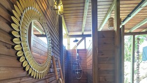 A wooden cabin interior with a large mirror, a wooden bench, and a sink.