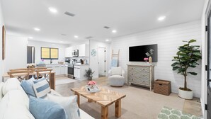 A modern living room with a sofa, coffee table, and a TV mounted on the wall. - Small Serenity 1•Fully Remodeled•Beach Gear•Bikes• (Miramar Beach)