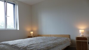A bedroom with a wooden bed, two bedside tables with lamps, a window, and a plain wall. - Apartment in riding center - 4 guests (Le Vernet)