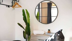 A bedroom with a bed, a bedside table with a book, a mirror, a hanging plant, and a towel. - 3 Bedroom with Parking, Close to Town Centre (Redcar and Cleveland)