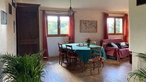 A dining area with a table, chairs, a hanging light fixture, and a world map on the wall. - Large chalet, parking, pets welcome - 11 guests near Vichy (Le Vernet)