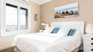A bedroom with a large bed, a window with a view, a painting on the wall, and a bedside table with a lamp. - Bright apartment with terrace and parking near the beach (Tarragona)