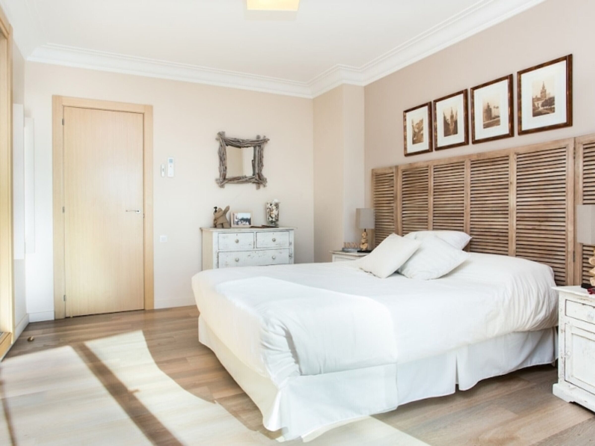 Un dormitorio con una cama grande, un aparador, un espejo y cuadros en la pared.
