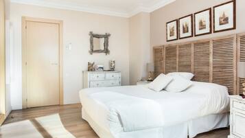 Un dormitorio con una cama grande, un aparador, un espejo y cuadros en la pared.