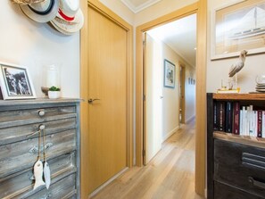 Ein Flur mit Holzboden, einer Holztür, einem Bücherregal mit Büchern und einem gerahmten Bild an der Wand.