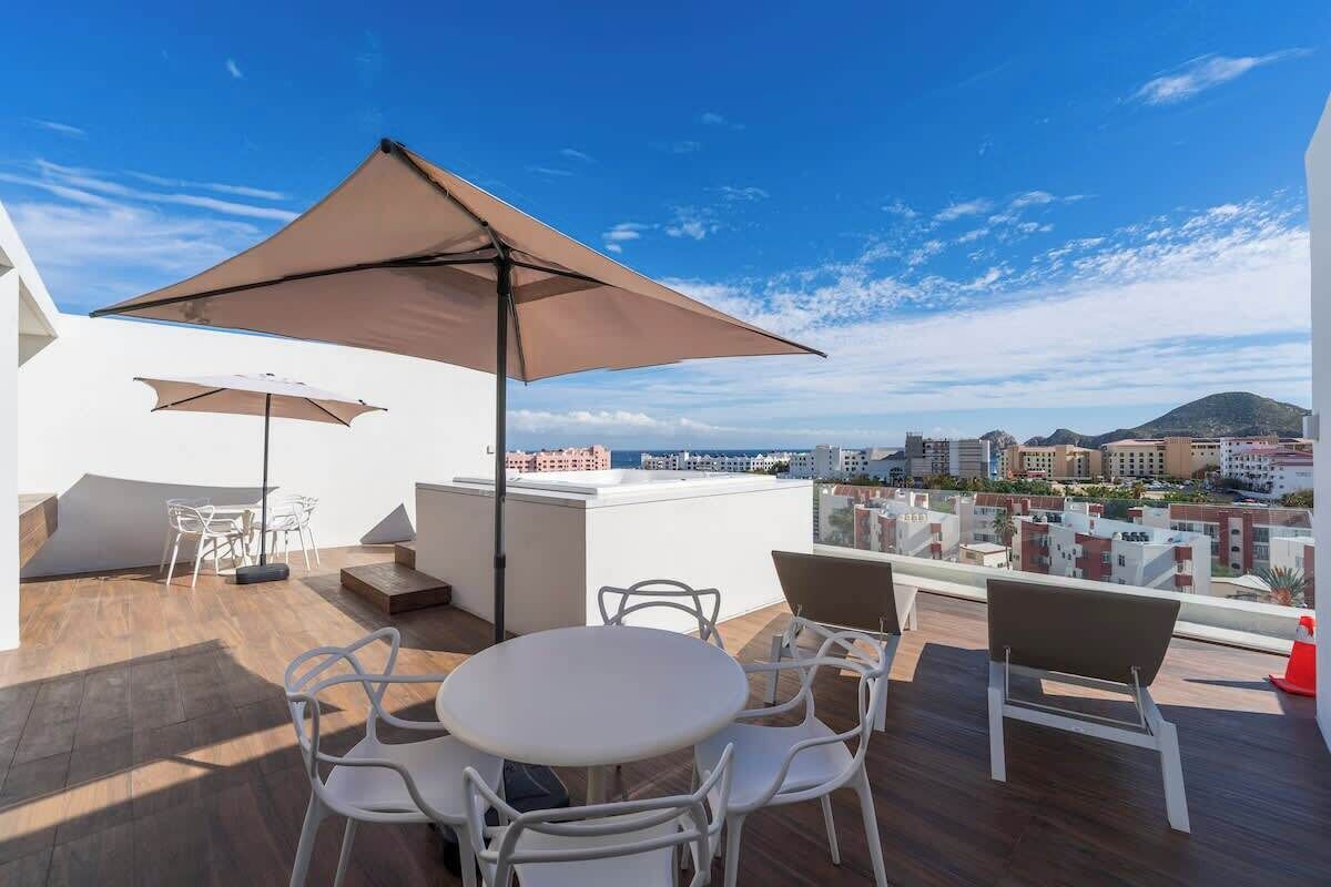 En takterrass med ett bord och stolar, ett stort parasoll och utsikt över stadsbilden.