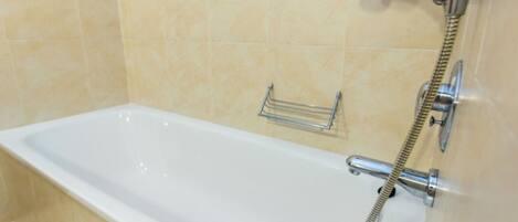 Una bañera blanca con un cabezal de ducha manual y un perchero para toallas.