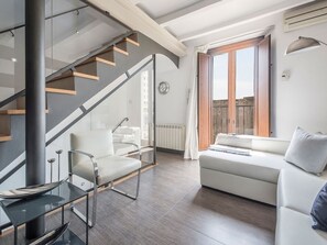 A modern living room with a glass staircase, a white sofa, a glass table, and a view of the outside. - Renovated townhouse in Tarragona center with sea view and terrace (Tarragona)