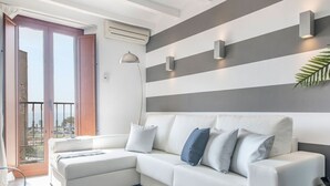 Een moderne woonkamer met een hoekbank, een glazen salontafel en uitzicht door een schuifdeur.