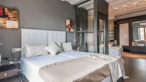 Een moderne hotelkamer met een groot bed, nachtkastje, kledingkast en een glazen scheidingswand.