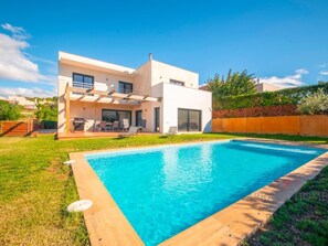 Ein modernes, zweistöckiges Haus mit Swimmingpool, Terrasse und Gartenmöbeln sowie einem gepflegten Rasen.