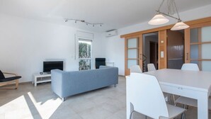 En moderne stue med sofa, fjernsyn og spiseområde med stole og bord.