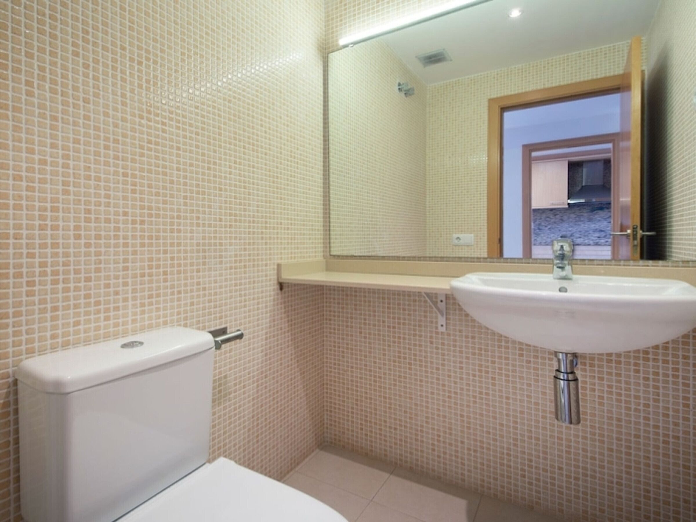 Un baño pequeño con inodoro, lavamanos y espejo.