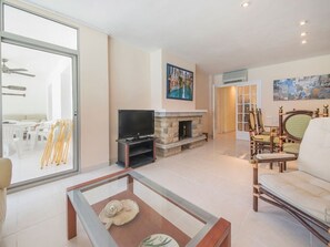 Ein geräumiges Wohnzimmer mit Kamin, Fernseher und einem Glastisch.