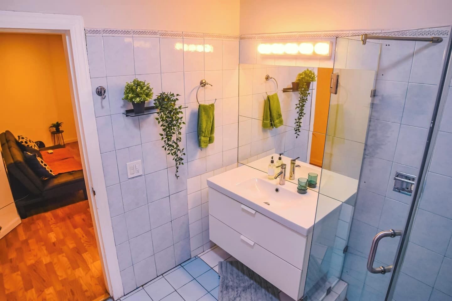 Highlighting the large mirror, shelves with plants, and neatly arranged towels, creating a fresh and organized style.