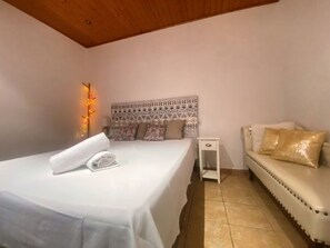 Une chambre à coucher comprenant un lit, une table de chevet, un canapé et une tête de lit décorative.