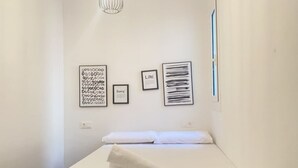 A minimalist hotel room with a bed, a wall-mounted light fixture, and three framed artworks. - Bright apartment in the historic center of Tarragona (Tarragona)