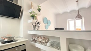 A kitchen with white cabinets, a stove, and shelves with kitchenware. - Bright apartment in the historic center of Tarragona (Tarragona)