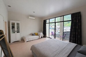Une chambre avec un grand lit, une armoire et un balcon équipé de chaises.