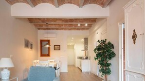 A spacious living area with a dining table and chairs, a sofa, a lamp, and a potted plant. - Modern 2-bedroom apartment in city center, Tarragona (Tarragona)