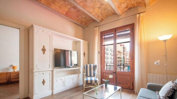 A living room with a television, a striped chair, a sofa, and a wooden cabinet. - Modern 2-bedroom apartment in city center, Tarragona (Tarragona)