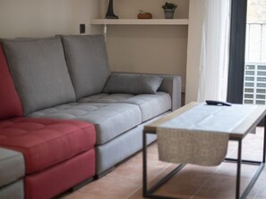Ein modernes Wohnzimmer mit einem grauen Sofa, einem roten Sessel und einem Holztisch.