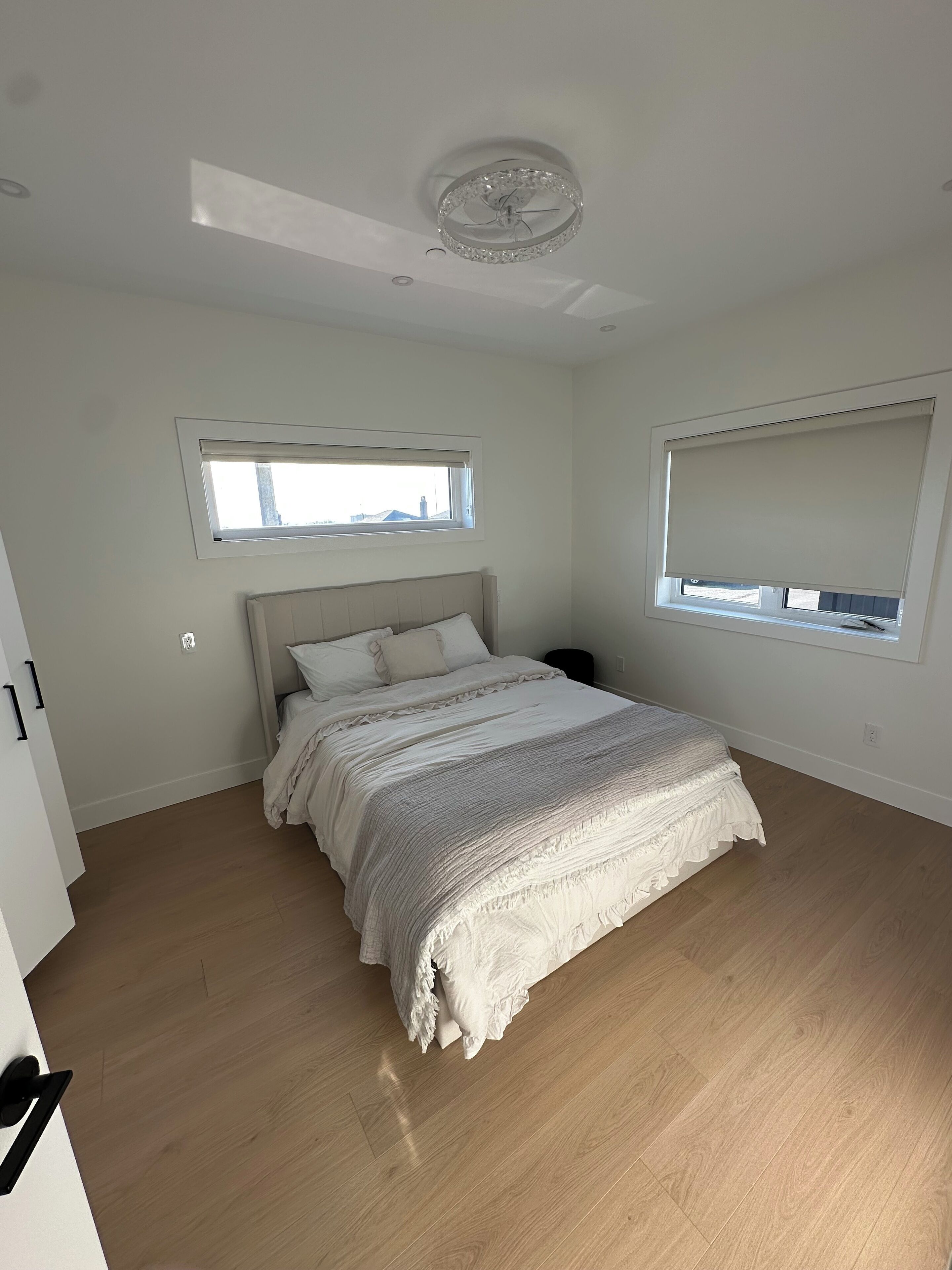 A bedroom with a bed, a ceiling fan, a window, and a door.