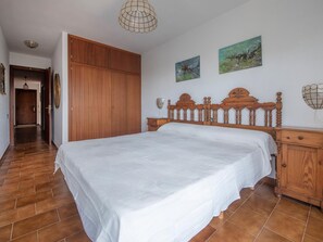 A bedroom with a wooden bed, a wardrobe, and two paintings on the wall. - Spacious villa in La Mora, 4 bedrooms, near the beach (Tamarit)