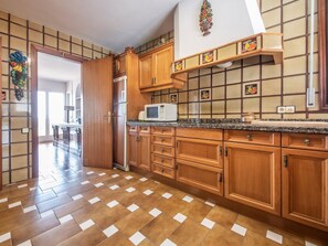 A kitchen with wooden cabinets, a microwave, and a tiled backsplash. - Spacious villa in La Mora, 4 bedrooms, near the beach (Tamarit)