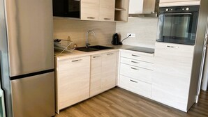 Cocina compacta con refrigerador, microondas, fregadero y estufa.