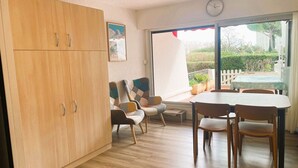 Una habitación amplia con un armario de madera, una mesa de comedor con sillas y un ventanal con vistas al exterior.