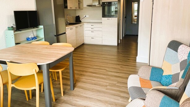 Una cocina moderna con comedor, televisor y sofá.