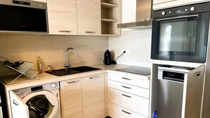 Una cocina compacta equipada con lavadora, lavavajillas, fregadero y estufa.