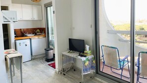 Cocina compacta con refrigerador, microondas y una pequeña mesa de comedor.