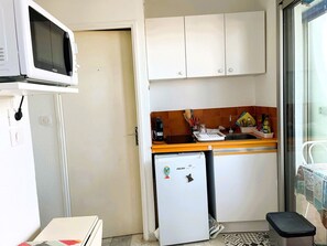 A compact kitchen with white cabinets, a microwave, and a refrigerator. - Cozy studio, AC and parking - 2 guests in La Grande-Motte (La Grande-Motte)
