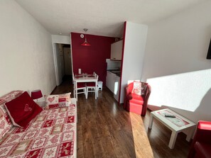 A compact living space with a dining area, a red sofa, a red armchair, and a small table. - Avoriaz - Renovated 4 pers apartment, balcony, equipped kitchen (Avoriaz)